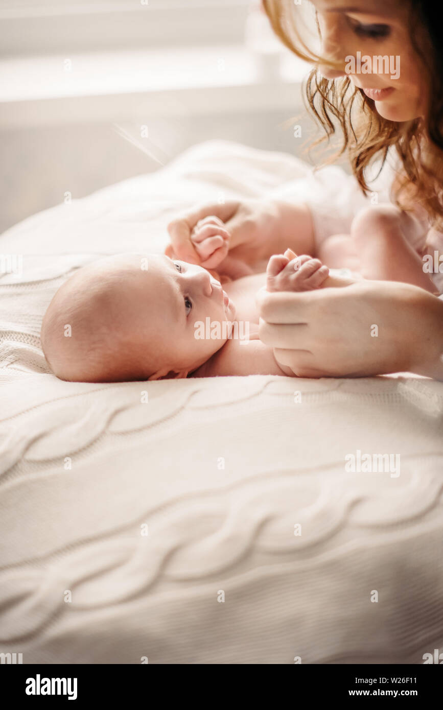 A young mother cares for and plays with a newborn baby Stock Photo