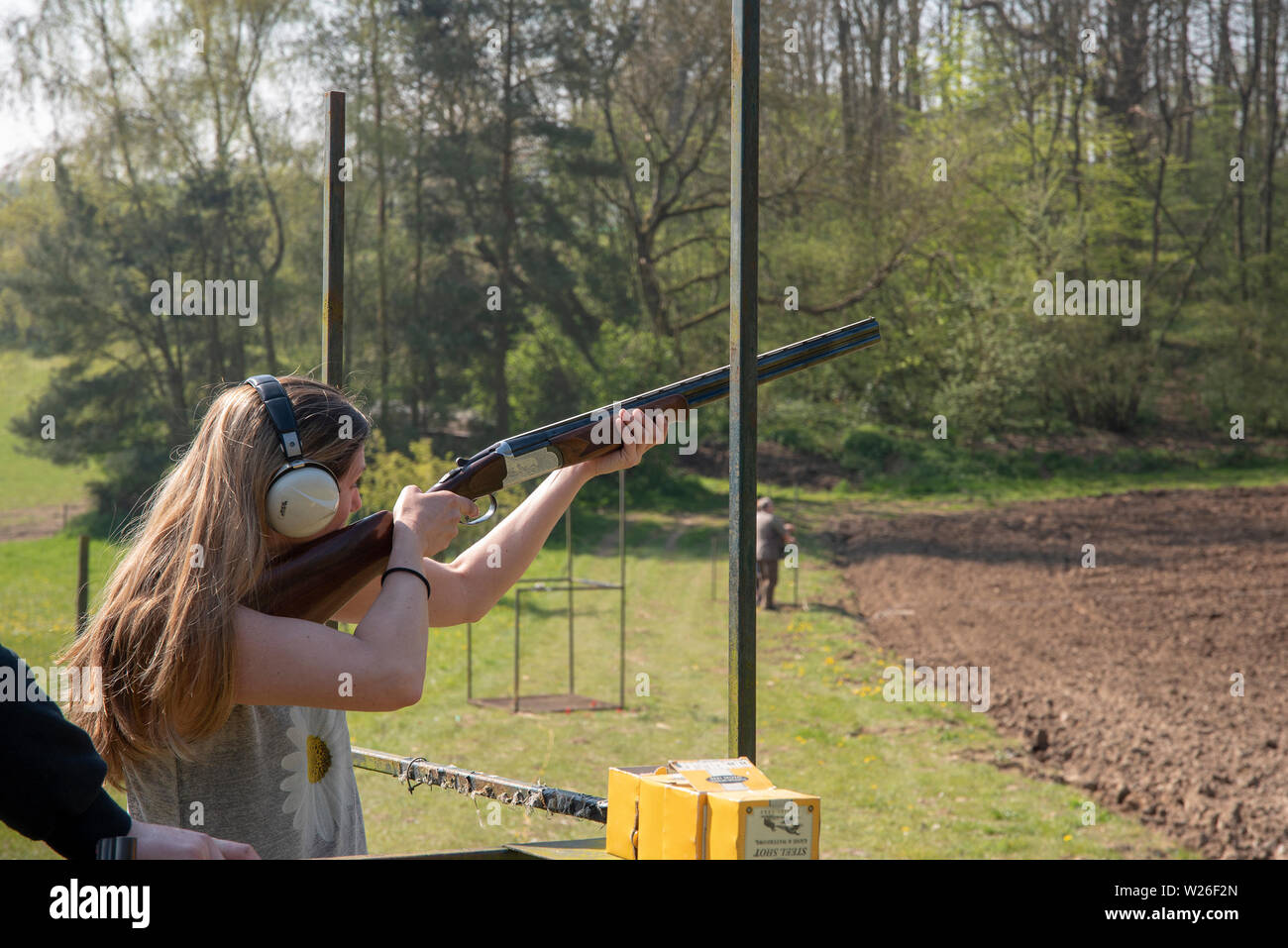 Woman/lady at a clay pigeon shoot with ear defenders taking aim Stock Photo