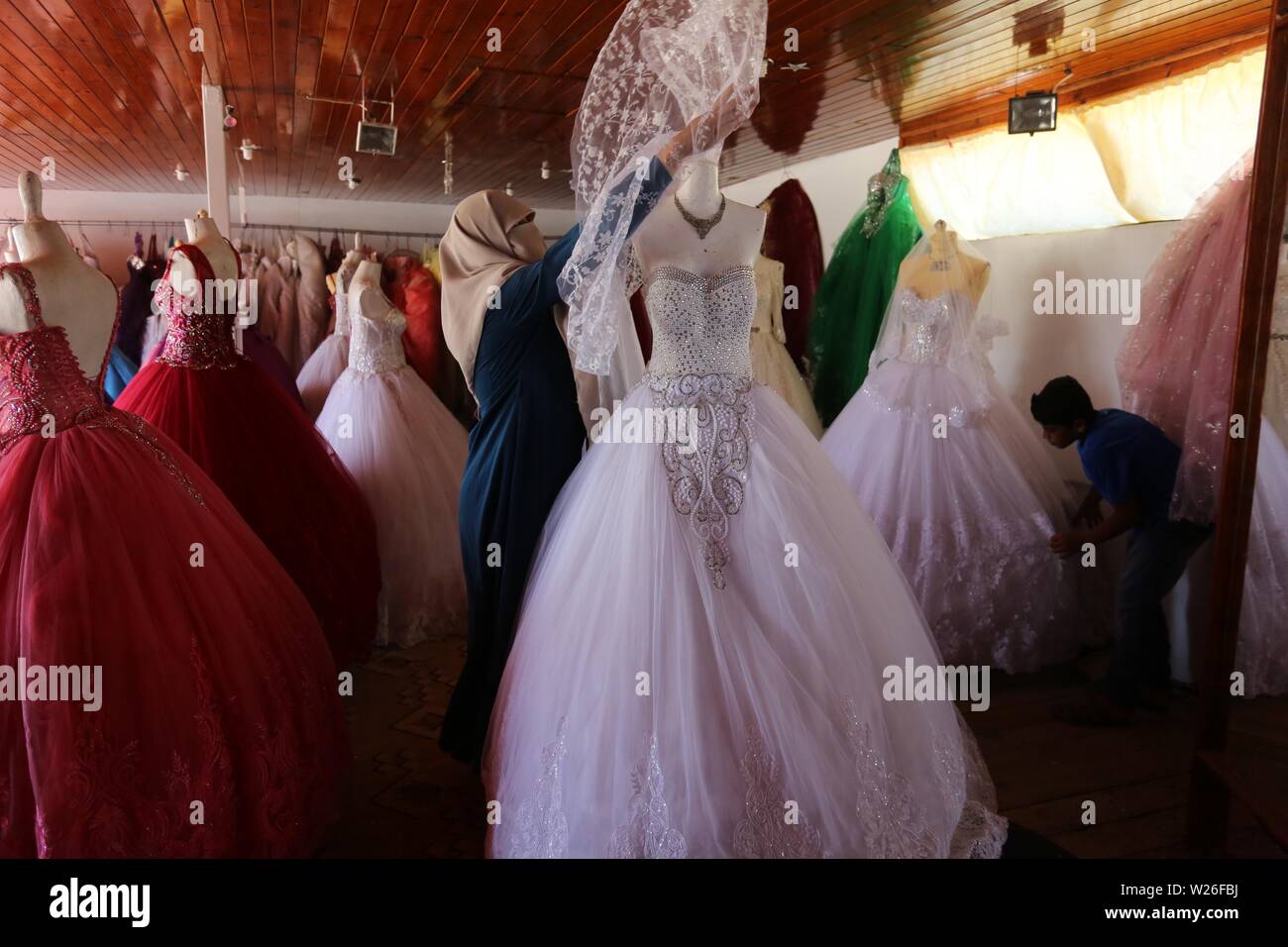 Khan Younis, Gaza Strip, Palestinian Territory. 6th July, 2019. Palestinian woman Sabrin al-Jabri, 34, works with her children at her shop in renting and selling wedding dresses, in Khan Younis in the southern Gaza Strip, July 06, 2019. Al-Jabri graduated from the Department of Medical Secretarial, she is currently studying at the Faculty of Law, chose to open a shop to rent evening dresses and wedding due to the collapsing economy in the Gaza Strip Credit: Ashraf Amra/APA Images/ZUMA Wire/Alamy Live News Stock Photo