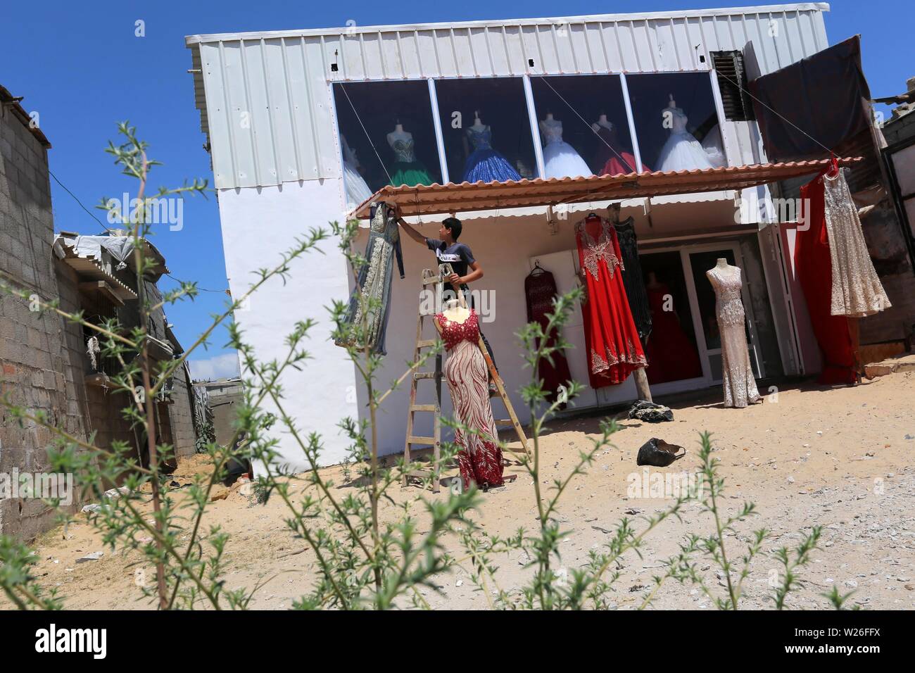 Khan Younis, Gaza Strip, Palestinian Territory. 6th July, 2019. Palestinian woman Sabrin al-Jabri, 34, works with her children at her shop in renting and selling wedding dresses, in Khan Younis in the southern Gaza Strip, July 06, 2019. Al-Jabri graduated from the Department of Medical Secretarial, she is currently studying at the Faculty of Law, chose to open a shop to rent evening dresses and wedding due to the collapsing economy in the Gaza Strip Credit: Ashraf Amra/APA Images/ZUMA Wire/Alamy Live News Stock Photo