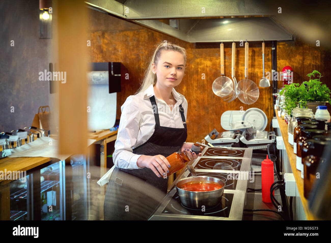 Chef adding condiments for taste in boiling pot with pasta sauce in restaurant kitchen Stock Photo