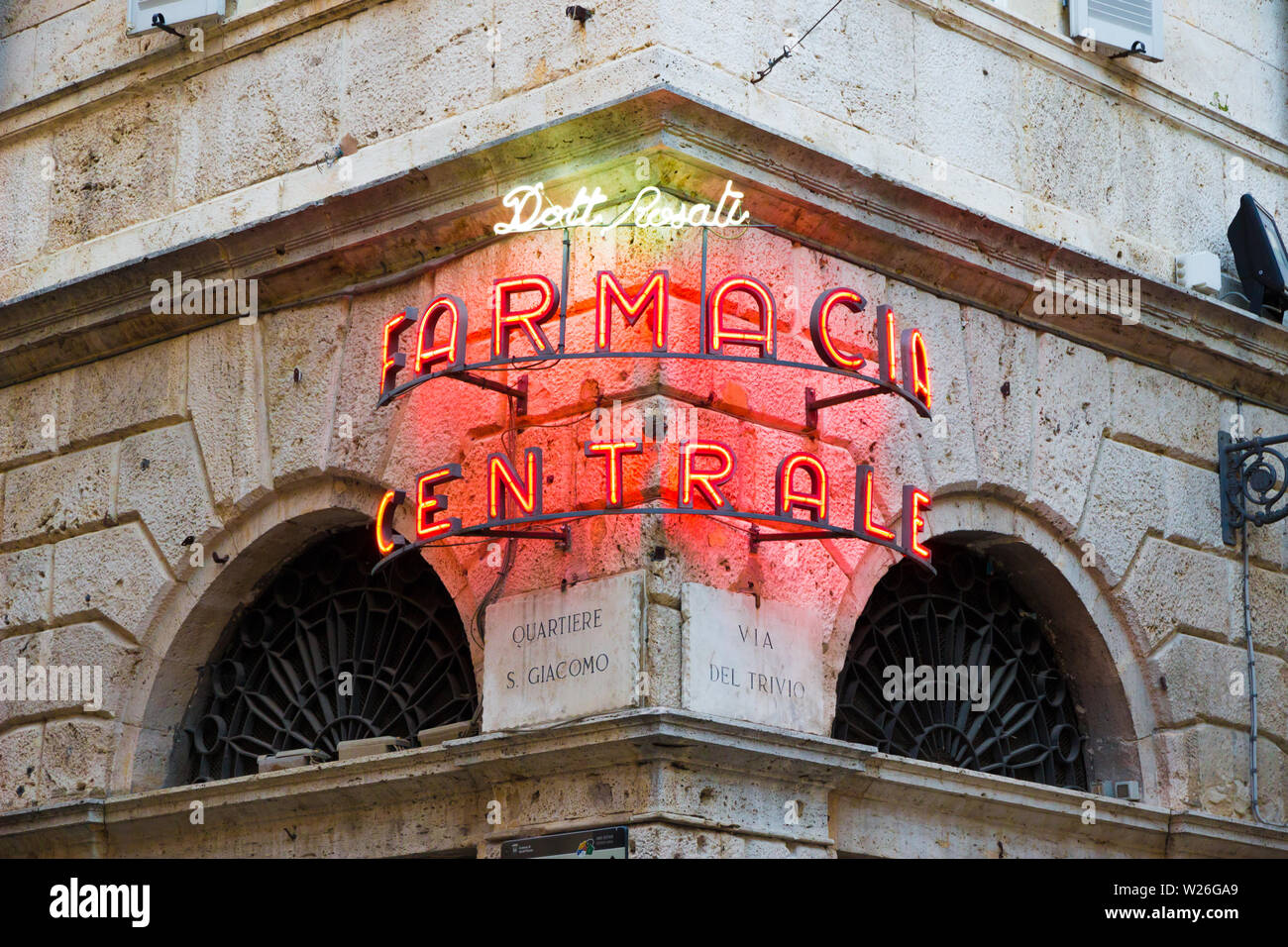 Ascoli Piceno, Italy - June 27, 2019: glowing neon sign in the old town readings: 'Doctor Rosati Central pharmacy' at sunset Stock Photo