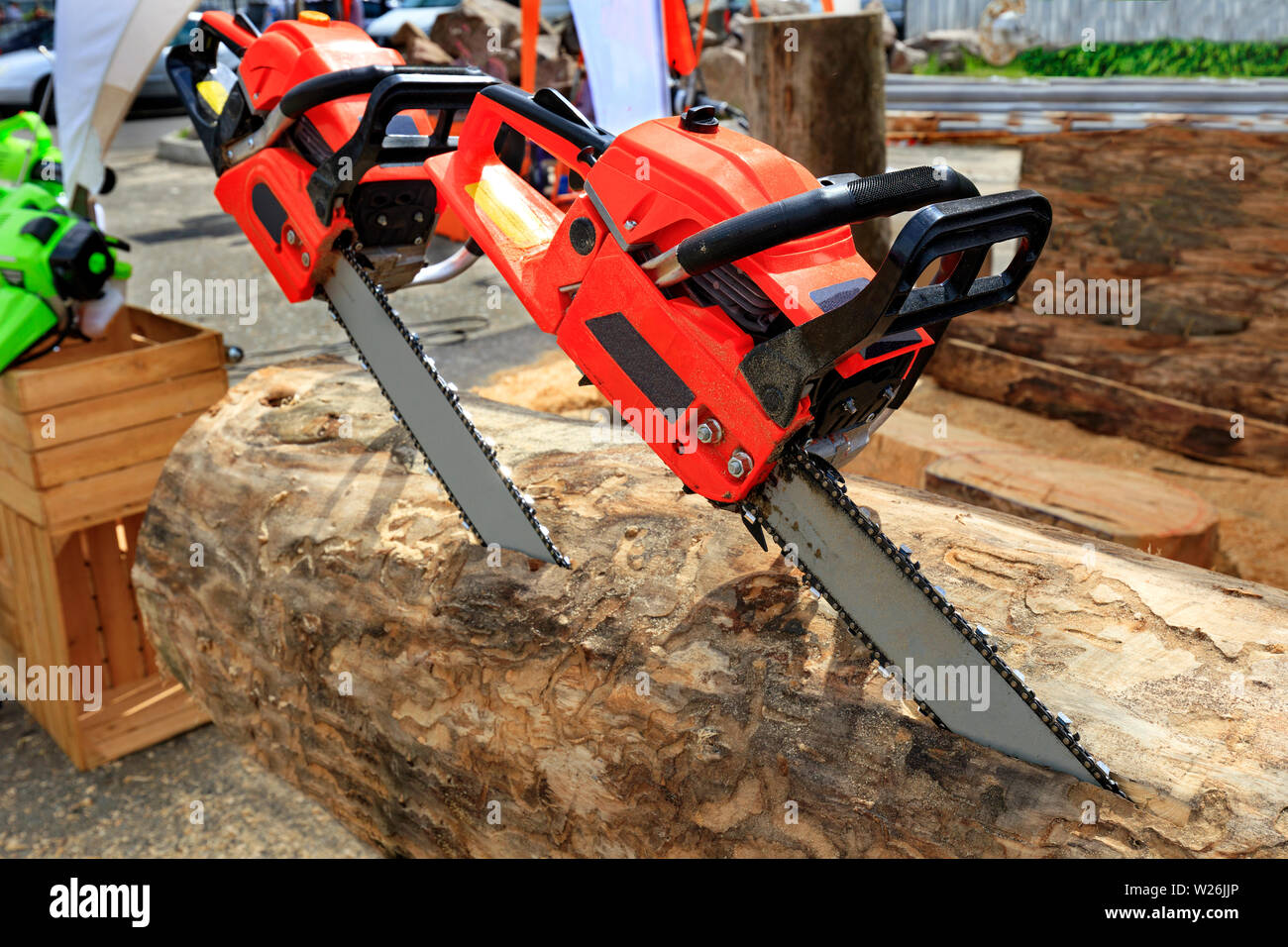Red powerful chainsaws protrude from the log. The concept of cutting