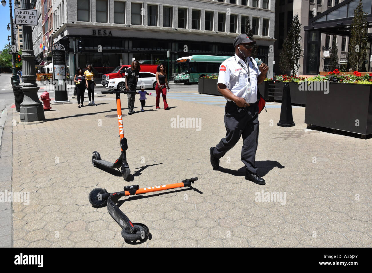 DETROIT, MI / USA - JUNE 30, 2019:  People walk past Spin scooters on a sidewalk in downtown Detroit. Stock Photo