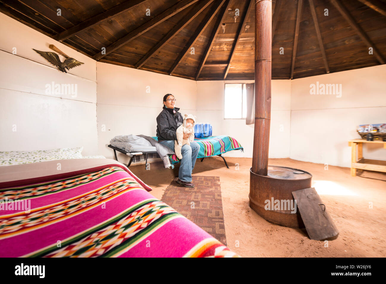 Navajo woman with child sitting on bed in traditional Hogan Stock Photo