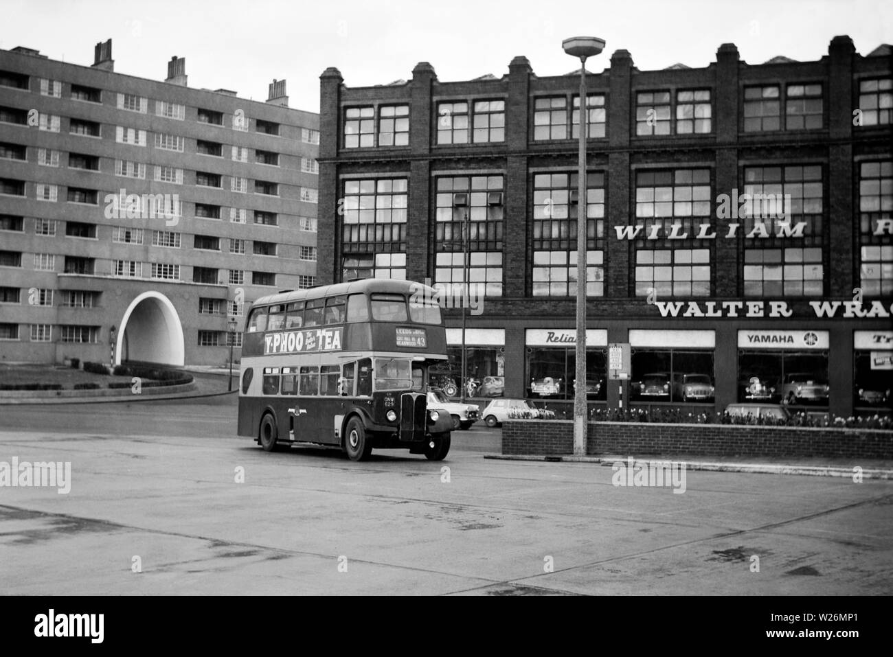 The cars on the right are in Duke Street. The factories dominating the background, right are William Read, Ltd, Wholesale costumiers and Walter Wragg Ltd. Motor Car Agents & Dealers, (Fiat), used car specialists, motor cycles, scooters and mopeds of Munro House, York Street. In the background left of centre the arched entrance to Priestley House, part of Quarry Hill flats is visible. Between 1938 and 1978 Quarry Hill was the location of what was at the time the largest social housing complex in the United Kingdom. Stock Photo