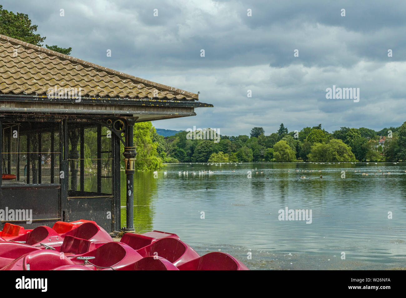 Roath Park Lake in the capital city of Wales, Cardiff, showing the surrounding trees and one of the boathouses, South Wales Stock Photo