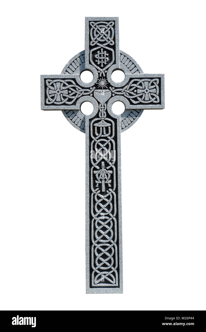 An ornate granite Celtic cross from the grave of a Roman Catholic priest, showing the Celtic knot pattern, a communion chalice, and the IHS symbol Stock Photo