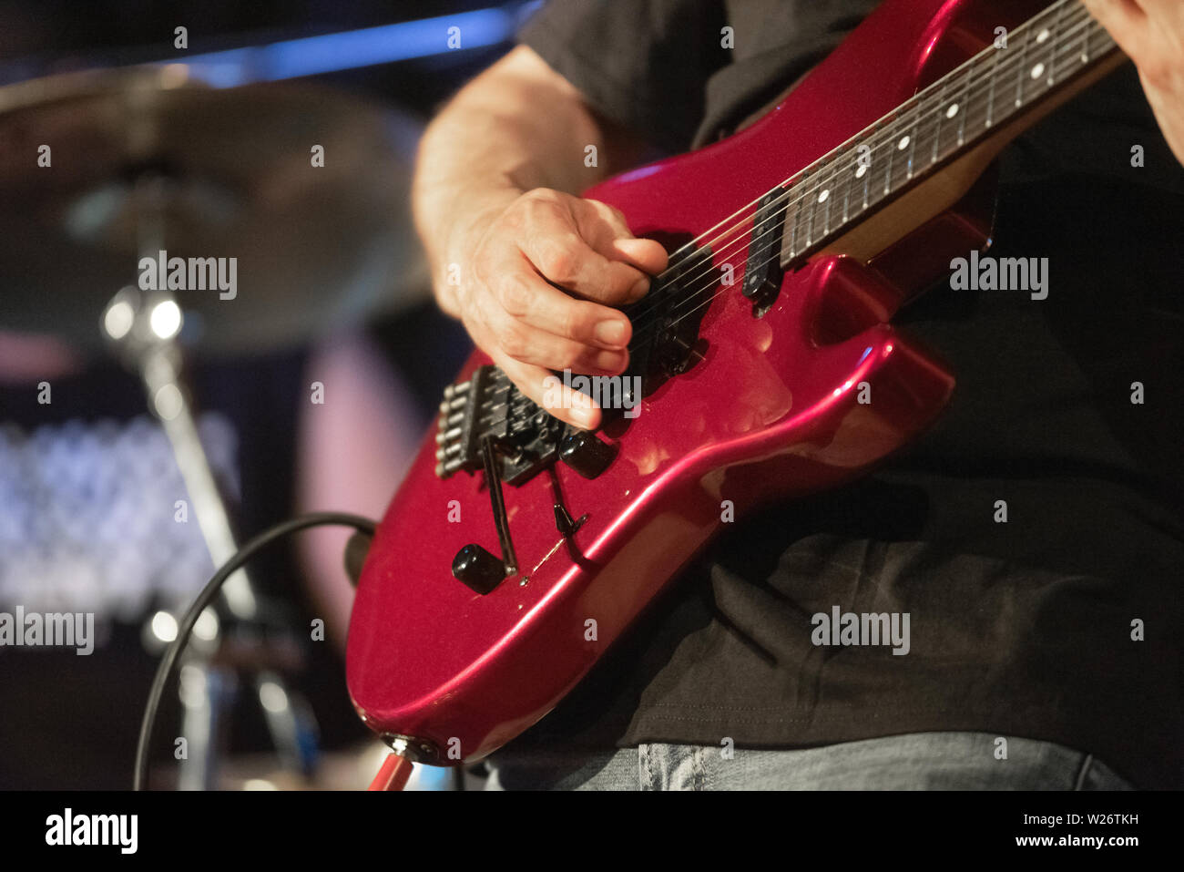 Man lead guitarist playing electrical guitar on concert stage Stock