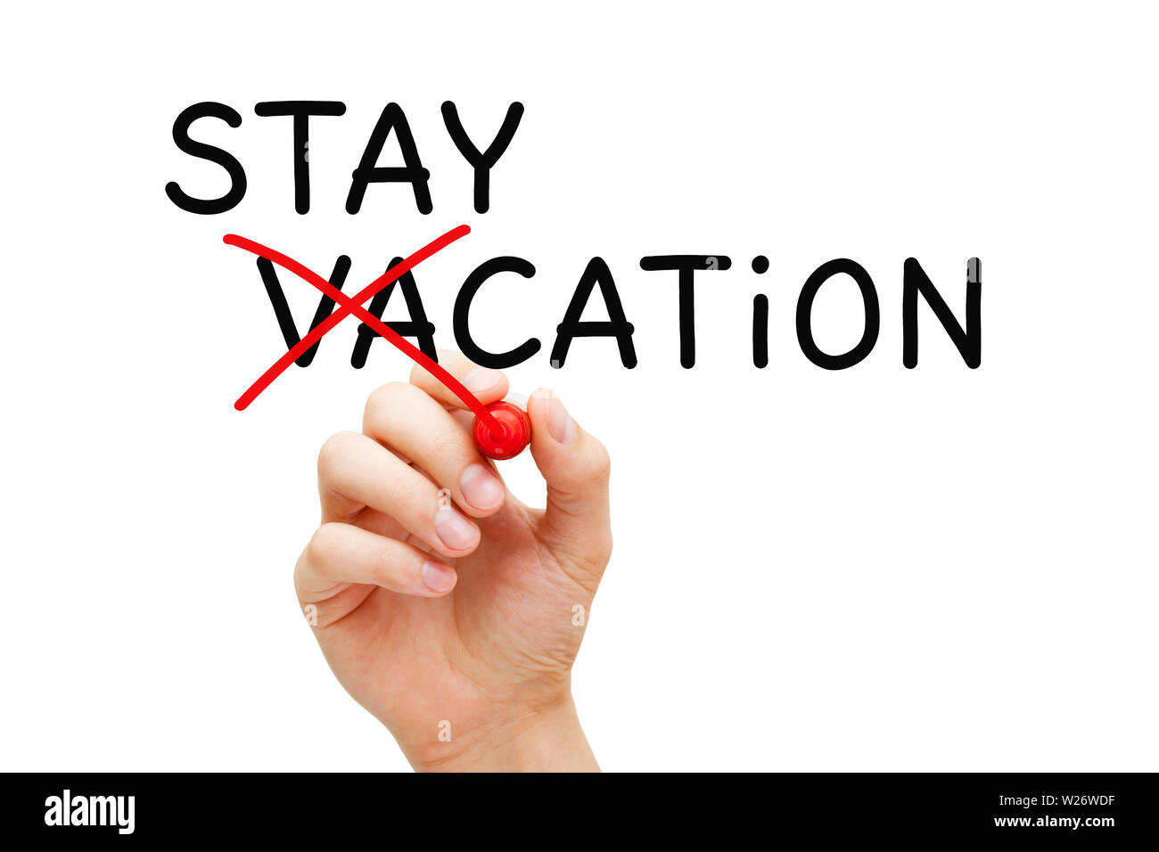 Hand turning the word Vacation into Staycation. Concept about spending a holiday at home or nearby rather than travelling to another place. Stock Photo