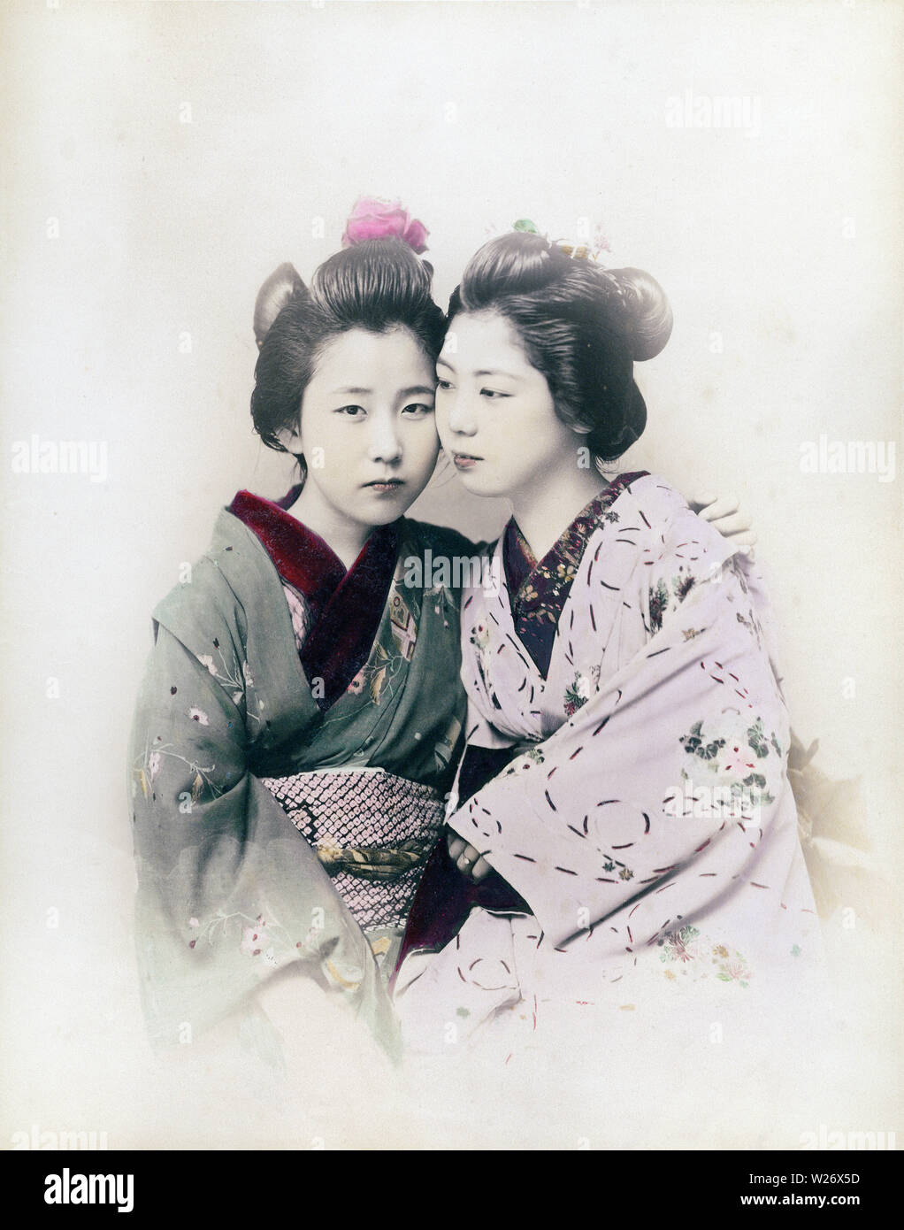 [ 1890s Japan - Two Japanese Women ] —   Two maiko (apprentice geisha) in kimono and traditional hairstyles in an intimate pose.  19th century vintage albumen photograph. Stock Photo