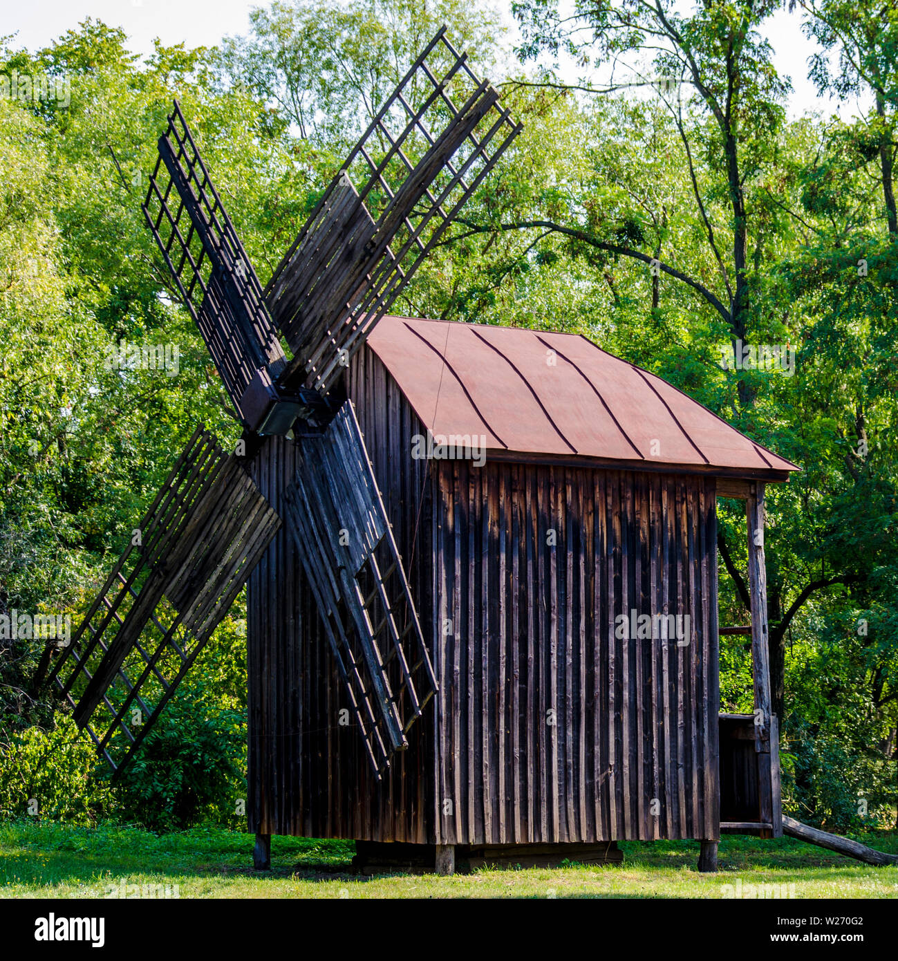 Old wooden windmill for grinding grain on green background Stock Photo