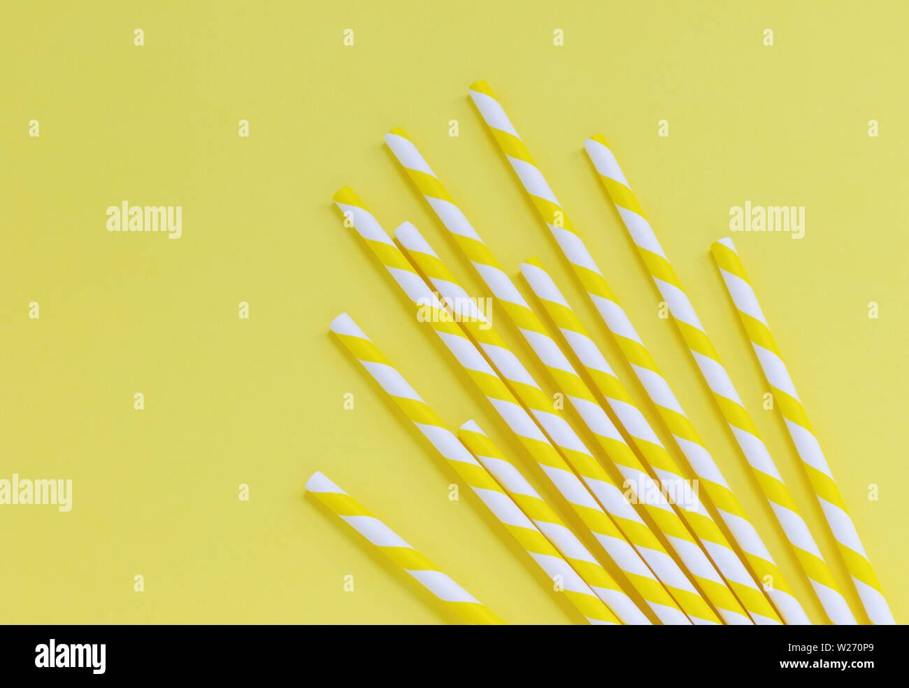 Yellow striped paper straws on a yellow background. Flat lay with copy space Stock Photo