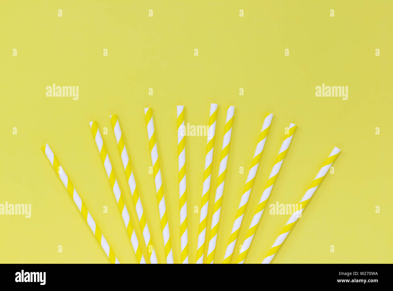 Fan of striped paper straws on a yellow background, with copy space Stock Photo