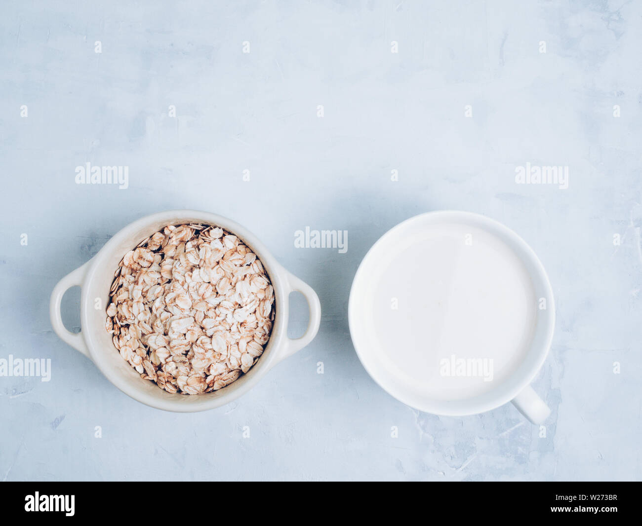 Oat milk drink in white cup and cereal flakes on kitchen bench. Flat