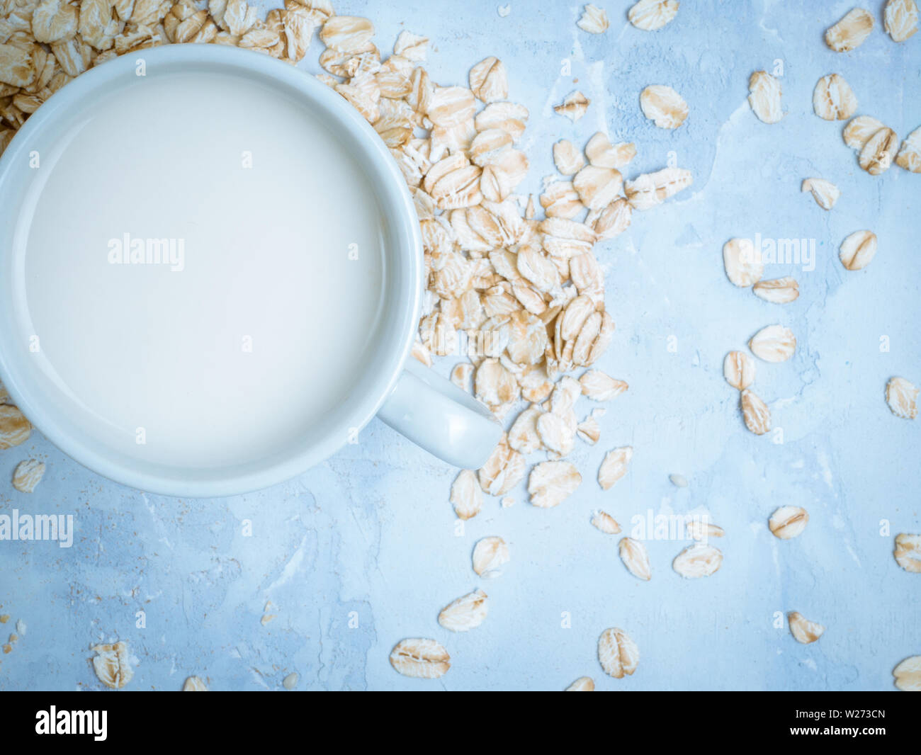 Oat milk drink in white cup and cereal flakes on kitchen bench. Flat lay. Copy space. Stock Photo