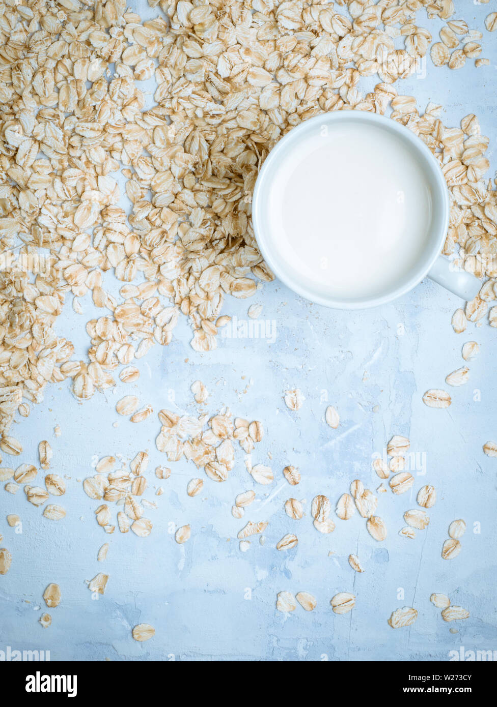 Oat milk drink in white cup and cereal flakes on kitchen bench. Flat lay. Copy space. Stock Photo