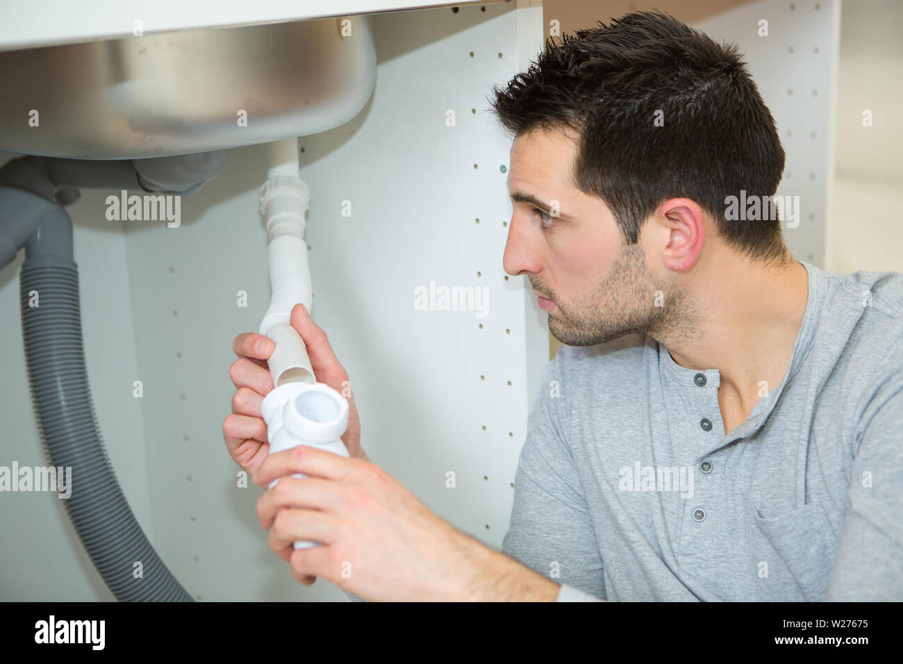 man fixing pipes under the sink Stock Photo Alamy