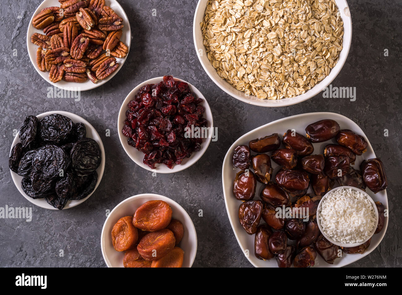 Ingredients for preparing Healthy organic energy balls- dates, dried apricot, oat flakes, raisin, dried cranberries, pecan nuts, coconut shavings on g Stock Photo