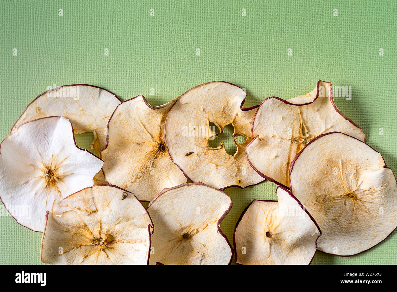Flat lay Baked Dehydrated dried Apples Chips over green background with
