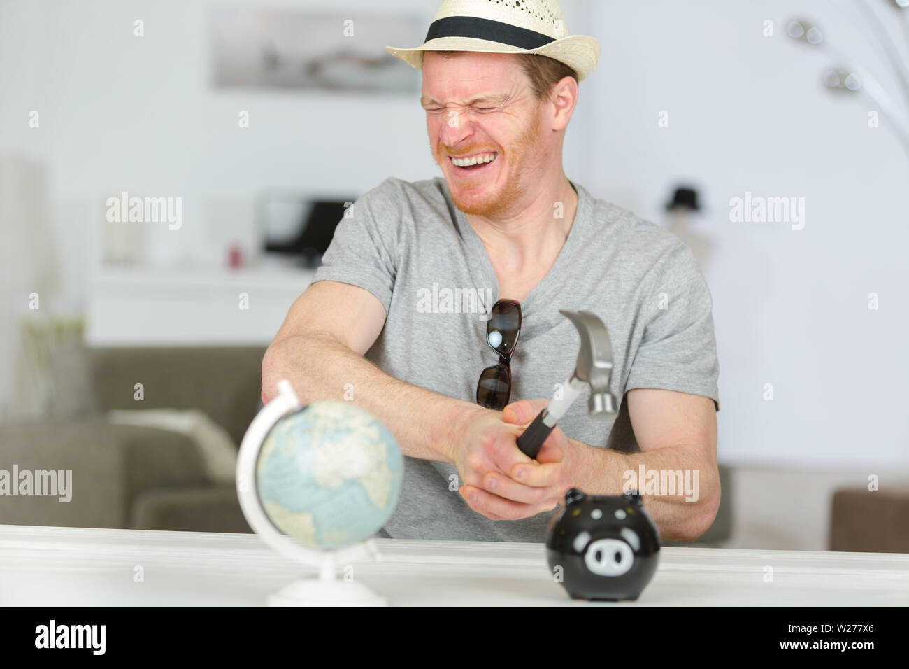 man breaking piggy bank with hammer Stock Photo - Alamy