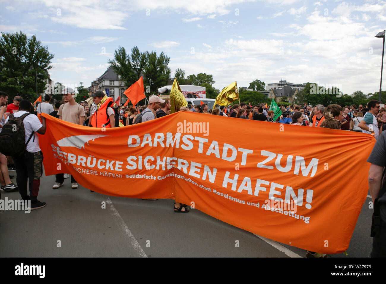 Frankfurt, Germany. 6th July 2019. Protesters carry a banner that reads  "Darmstadt as a save habour". Over 1,000 people marched through Frankfurt,  to call for save refugees routes, an end to the