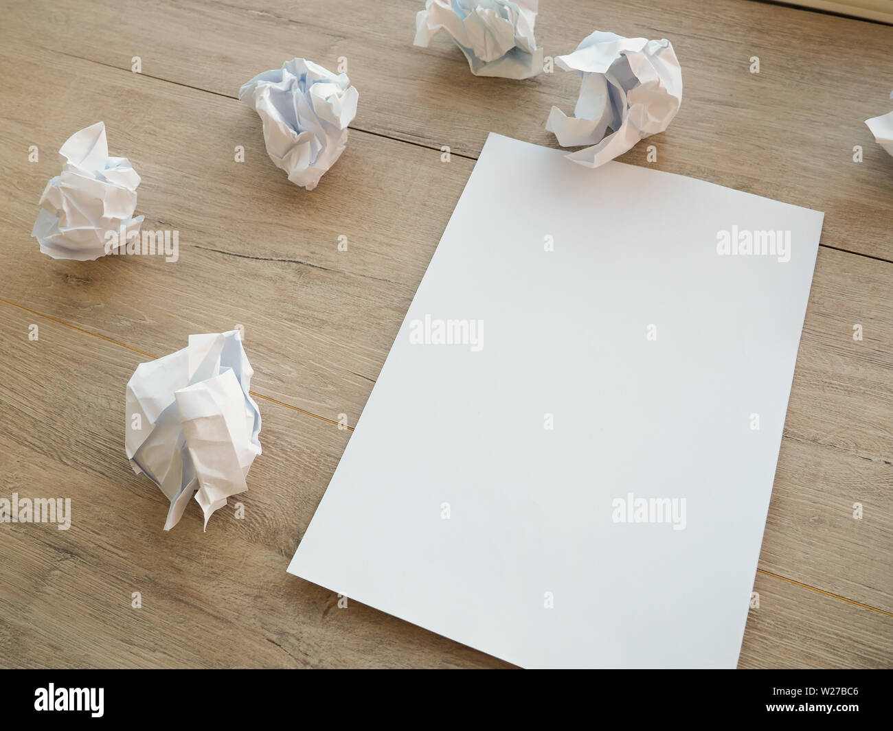 Writing concept crumpled up paper wads with a sheet of white paper