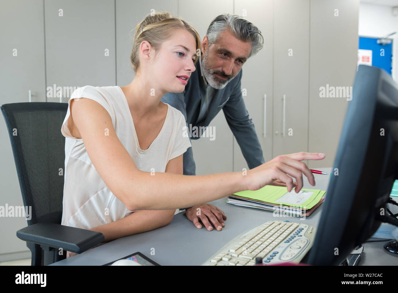 mature businessman advising young woman at computer desk Stock Photo ...