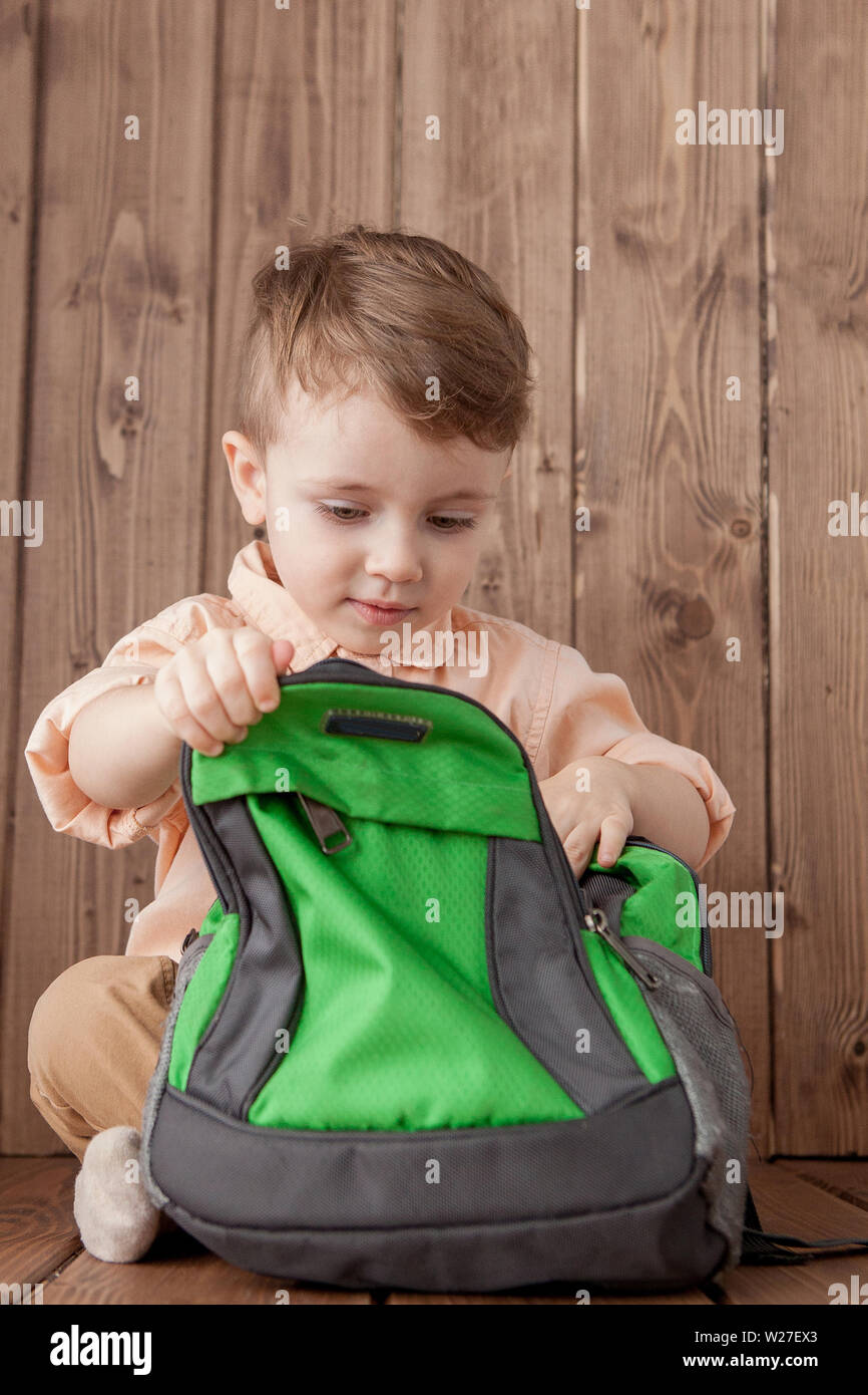 Little boy with large school bag on wooden background Stock Photo Alamy