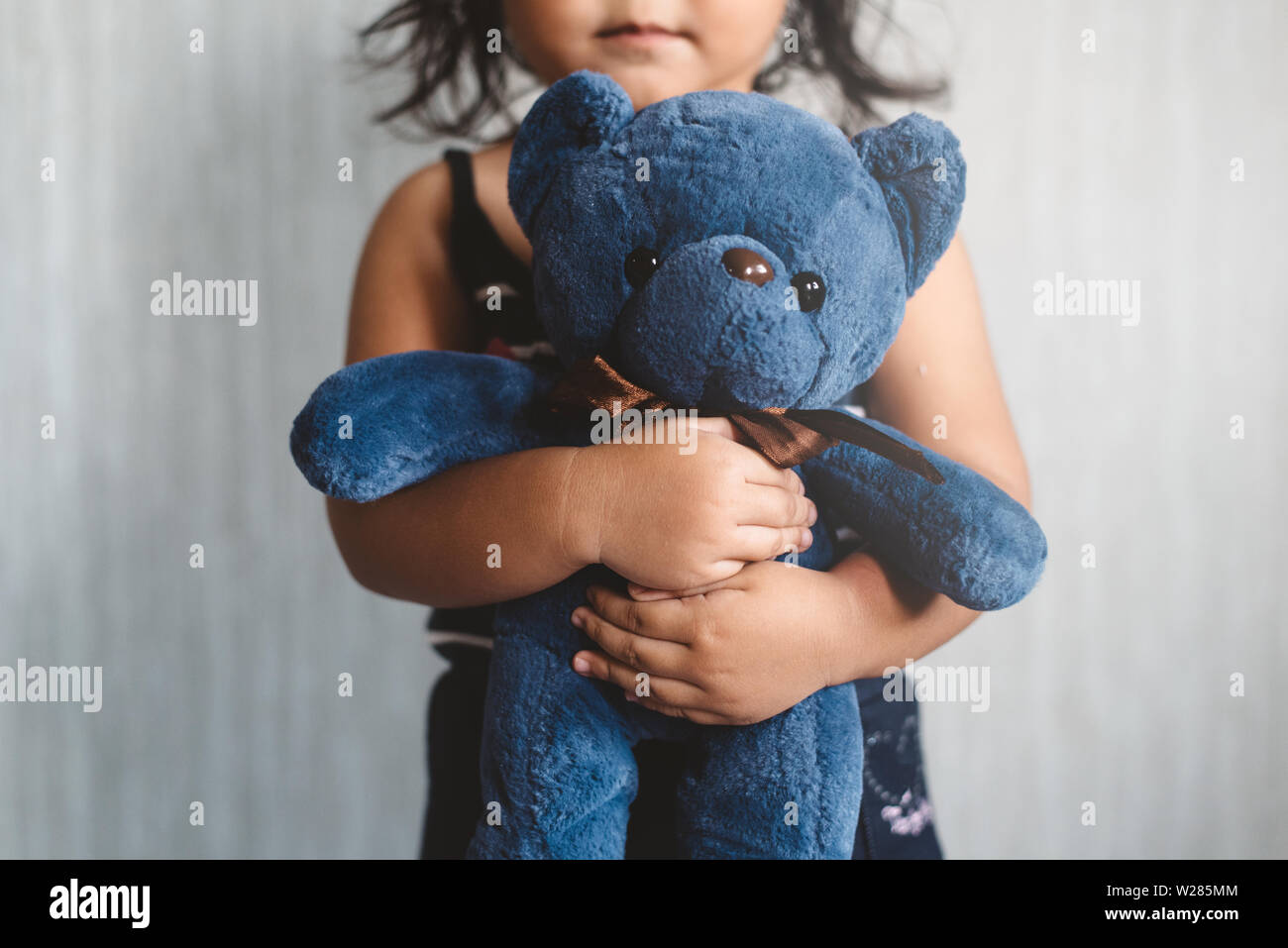 sweet little asian girl hugging her favorite toy teddy bear. Concept of Lonely child, love, childhood and parenting. Selective focus on the plush toy. Stock Photo