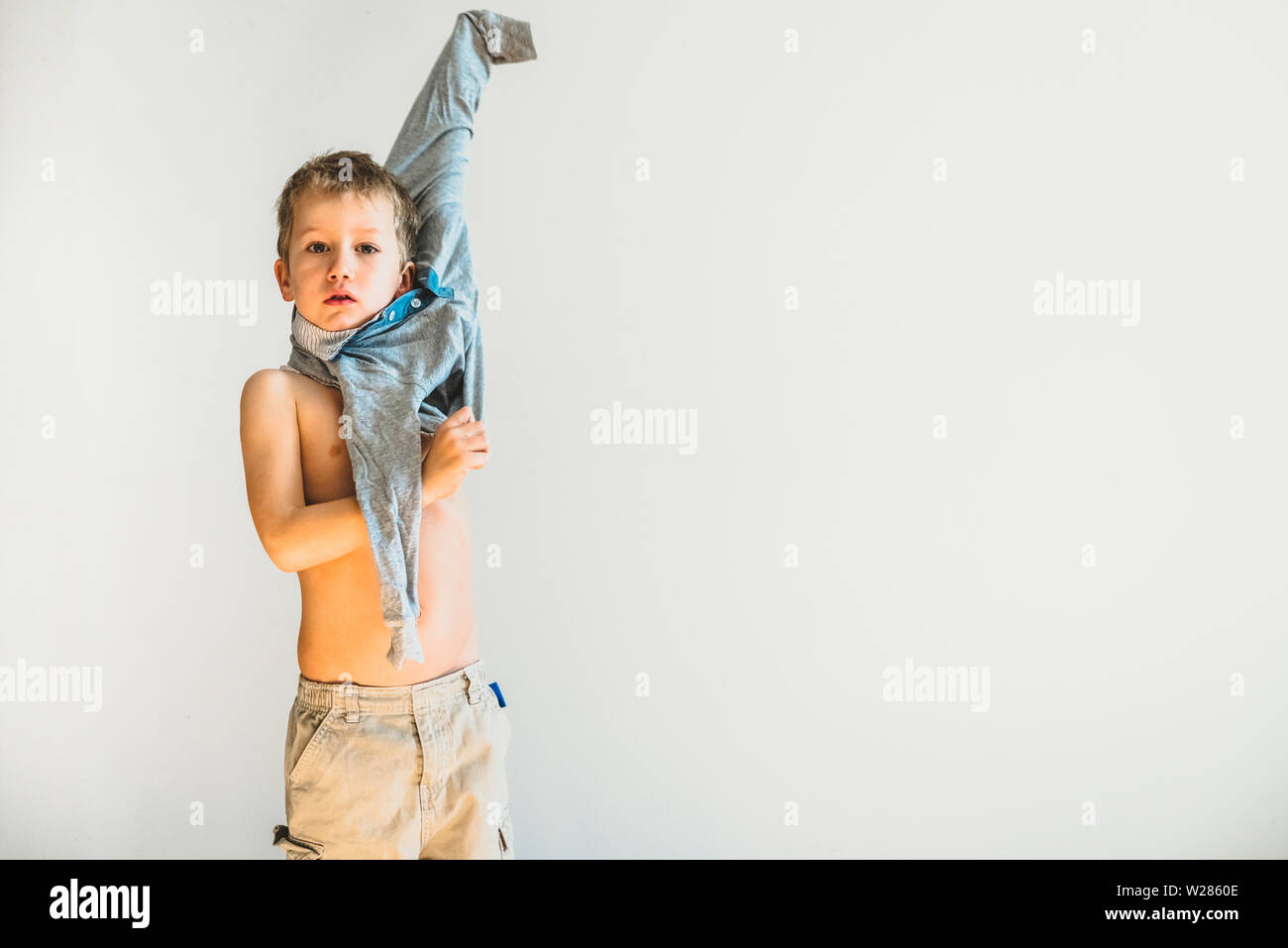 child-trying-to-take-off-his-shirt-and-undress-on-his-own-stock-photo