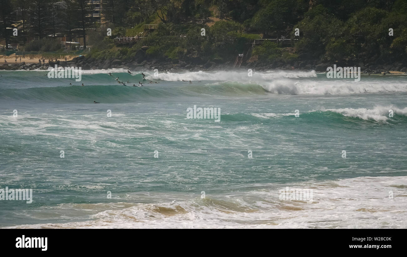 long shot of surfers riding waves at greenmount on the gold coast of queensland Stock Photo