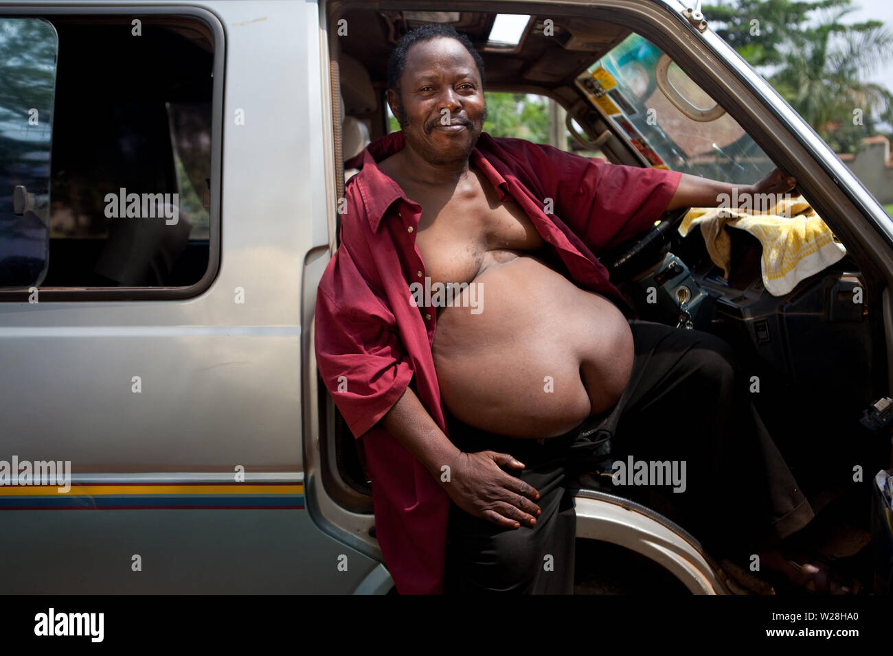 July 2, 2011 – Kampala, Uganda - Moses Kawooya is a 59-year-old obese Ugandan man. He weighs 110 kilos. Kawooya is a dancer and the chairman of the group Sanyu African Music and Dramatic Society (SAMADS). Ugandan President Yoweri Museveni calls him to perform whenever he hosts foreign Presidents such as US Presidents Bill Clinton and George Bush, Nigerian President Olusegun Obasanjo and Rwandan President Paul Kagame, ministers and other dignitaries in Uganda.  Kawooya says his big belly is genetic. His dad and his grandfather had the same physique. He takes pride in his enormous belly, saying Stock Photo