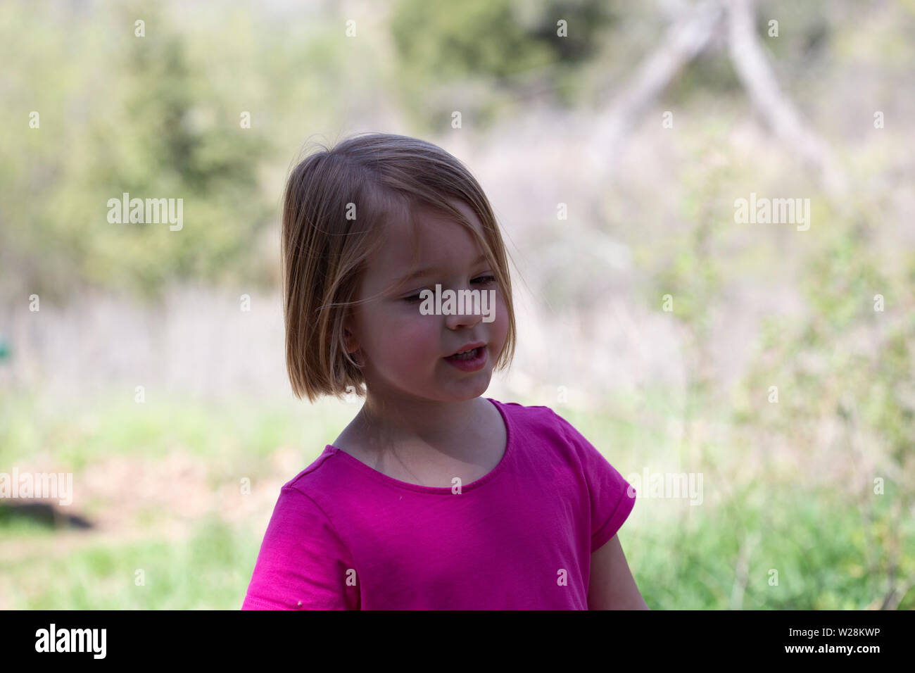 Close up of young girl in pink dress playing in the outdoors Stock Photo