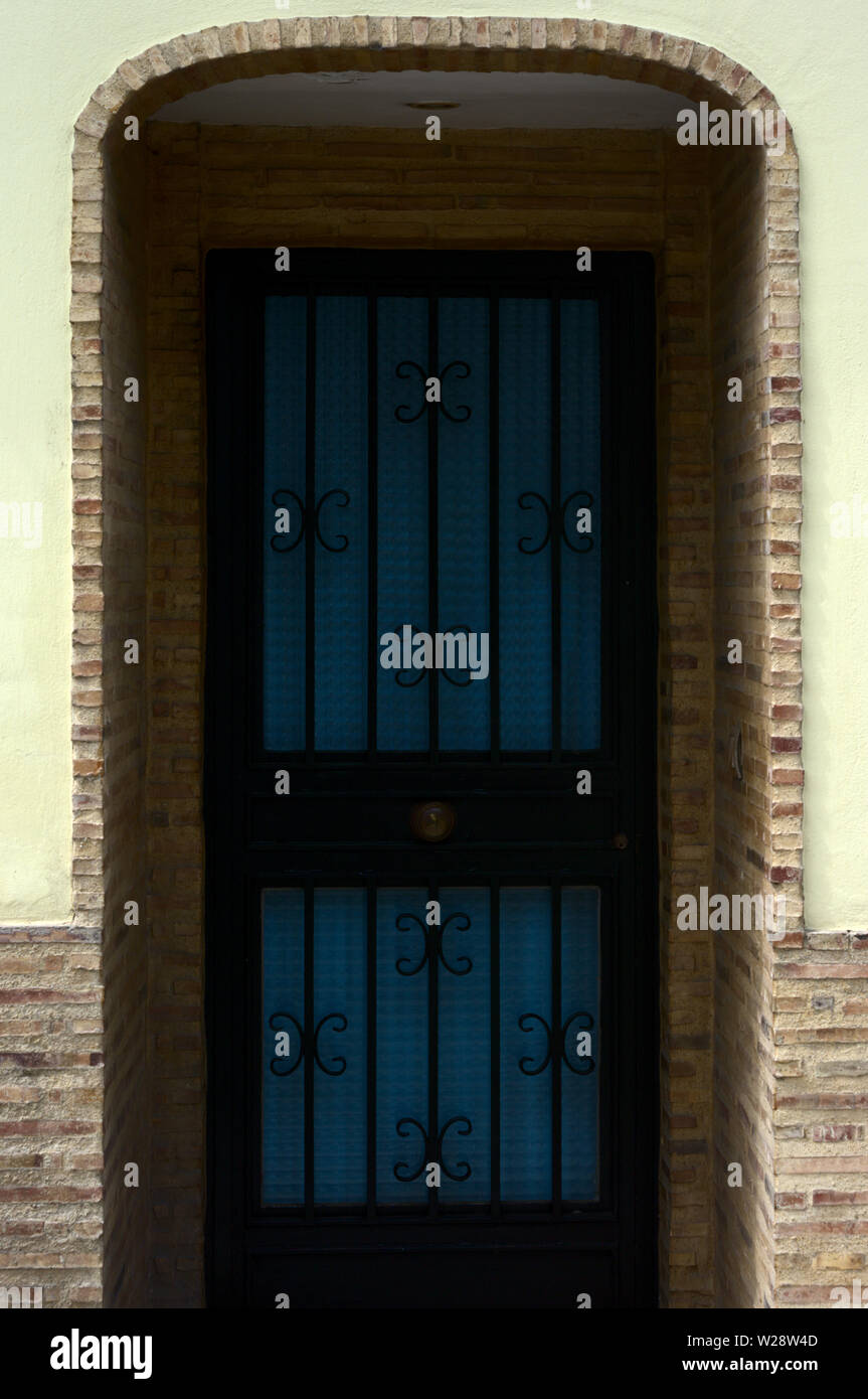 Entrance with blue and black door with facade of stone and yellow wall Stock Photo