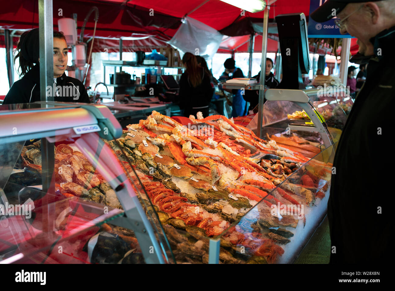 A saleswoman selling fresh seafood to a customer at the fish market in Bergen, Norway. Stock Photo