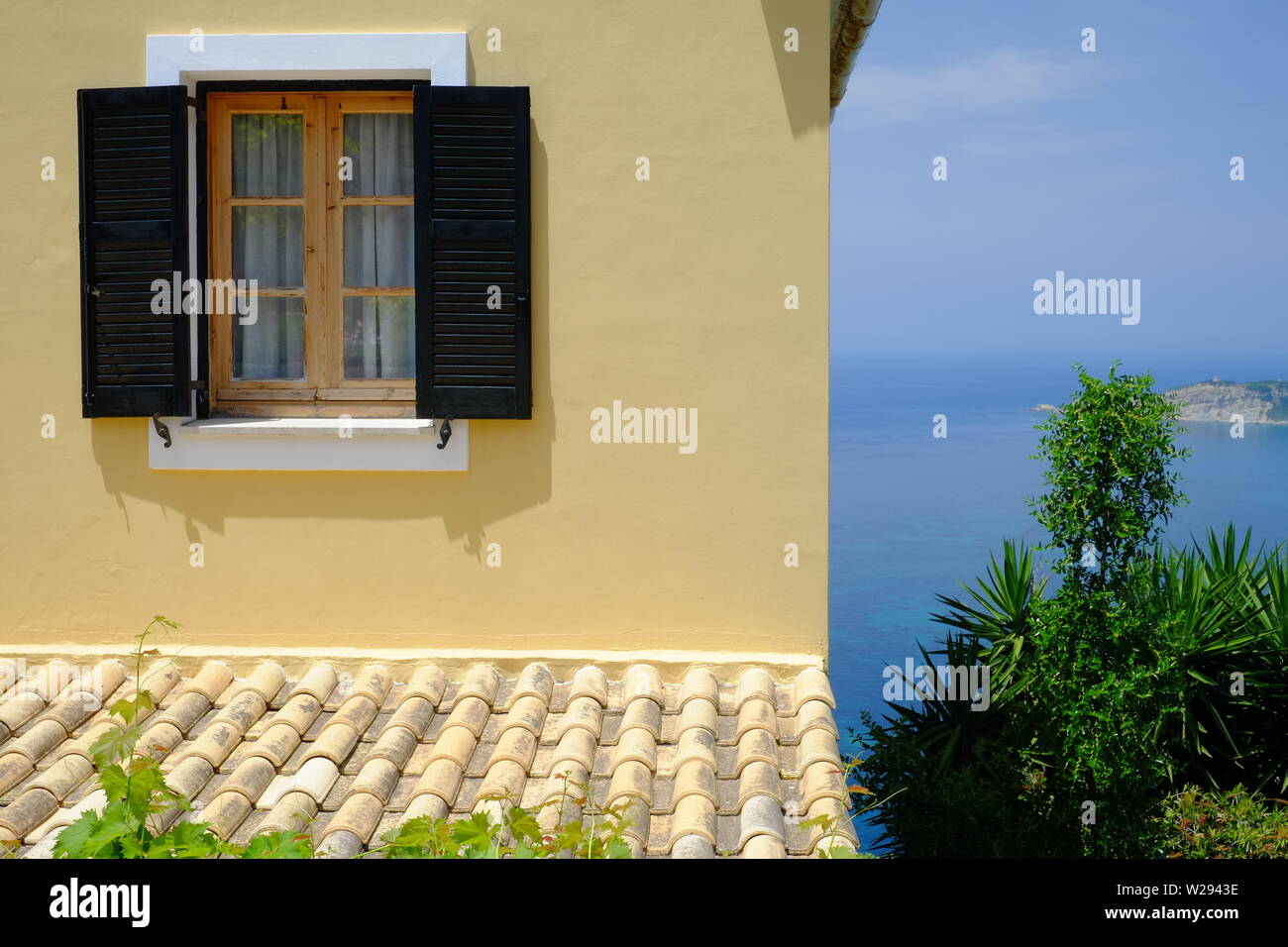 restored house painted yellow sun brightening the walls with  a great sea view situated in the old scenic village of Afionis Corfu Stock Photo