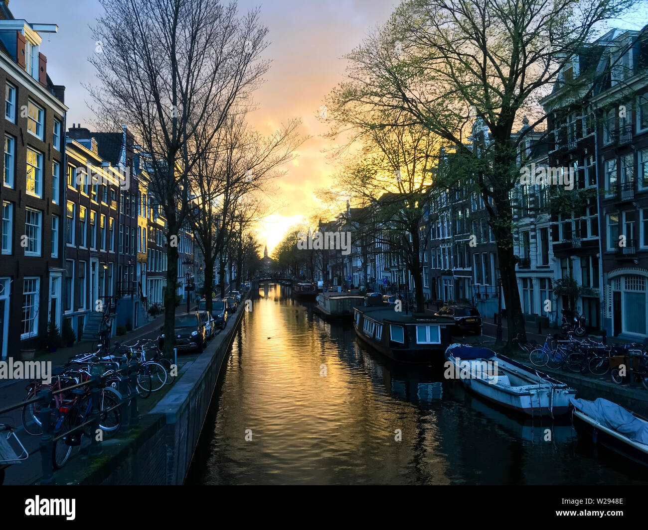 The winter sun is rising on an old town canal in Amsterdam's historic Jordaan residential neighbourhood. Stock Photo