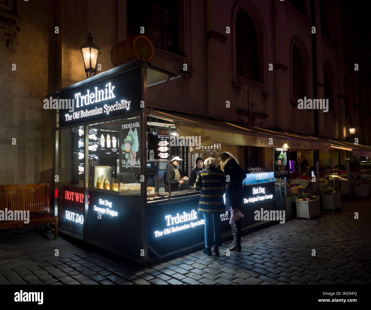 Ambulant vendor in the inner city, Stare Mesto, Prague Czech republic offering the traditional sweet pastry Tdrelnik to nighttime strollers Stock Photo