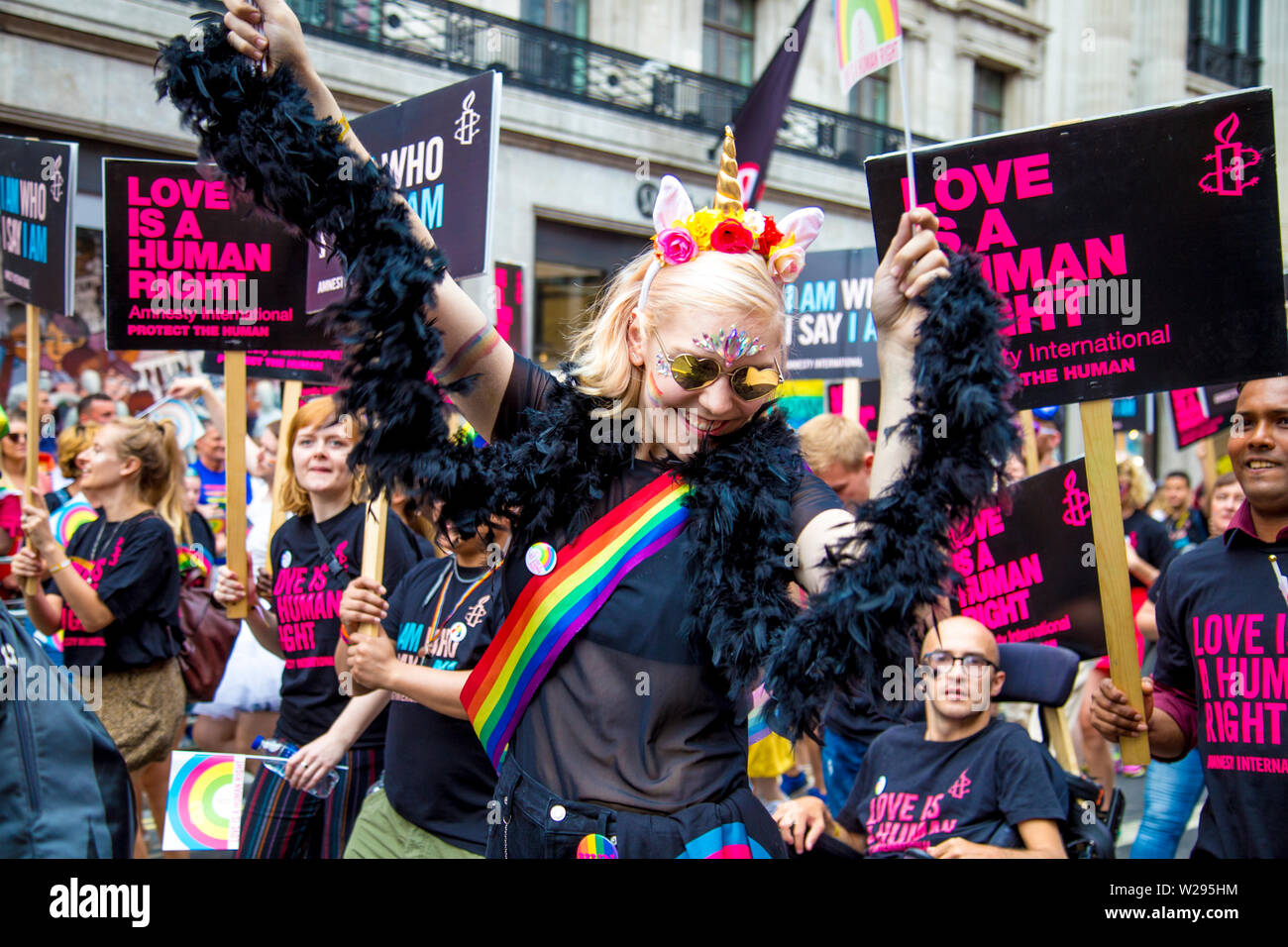 6 July 2019 - Woman with unicorn aline band and heart-shaped glasses,  dancing, London Pride Parade, UK Stock Photo