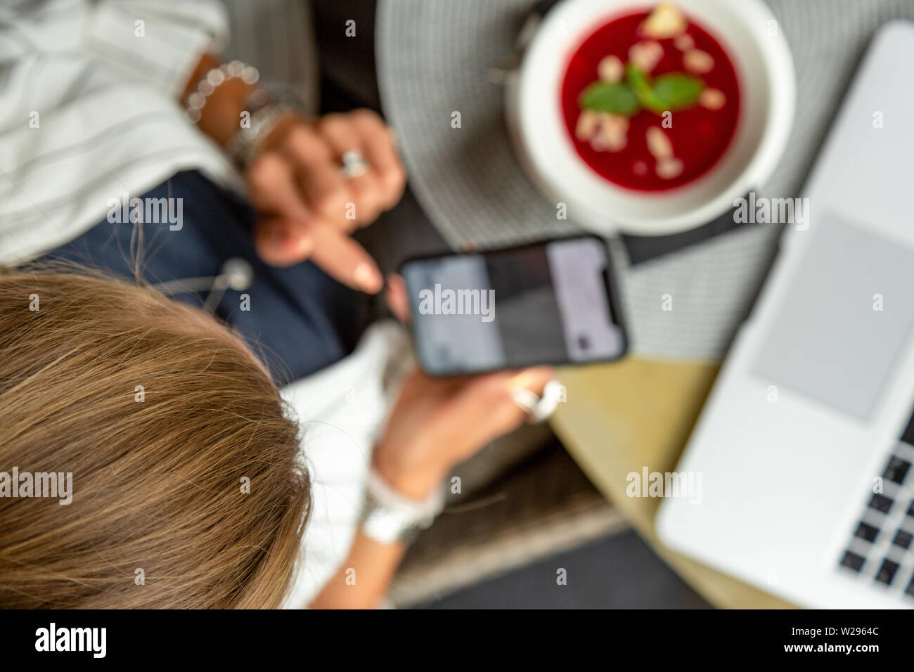 Businesswoman working during the lunch with salad sitting at the vegan restaurant on the beautiful green wall background Stock Photo
