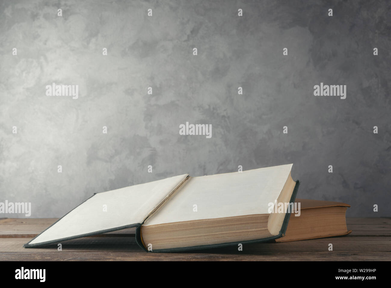 Open books on the table against the wall Stock Photo