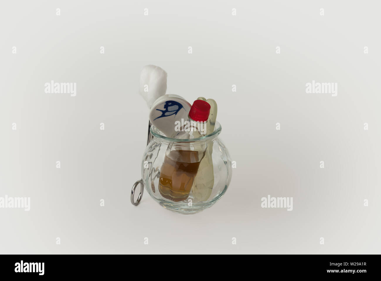Fire cupping jar containing bottle of oil, Chinese soup spoon and fish shaped jade Gua Sha stone. Forceps with cotton wool rest outside of the cup Stock Photo