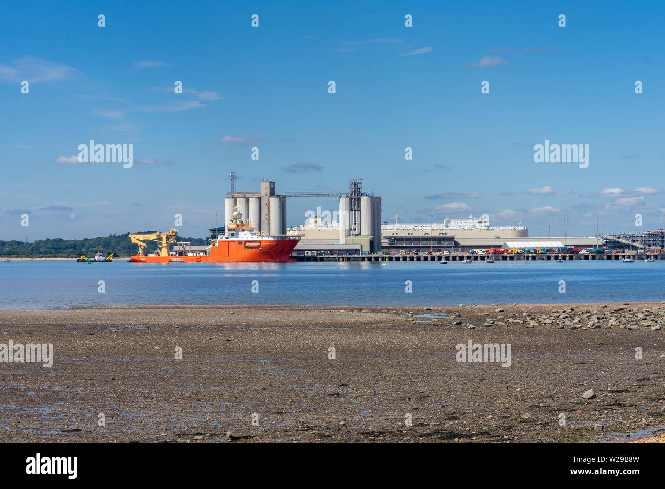 Low tide along Weston shore with view to Southampton Eastern Docks with the Normand Pacific - an off shore construction vessel moored, Southampton, UK Stock Photo