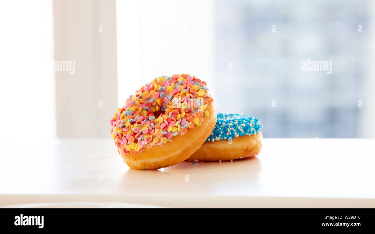 Donuts for breakfast. Colorful donuts on white table. Close up view, copy space Stock Photo