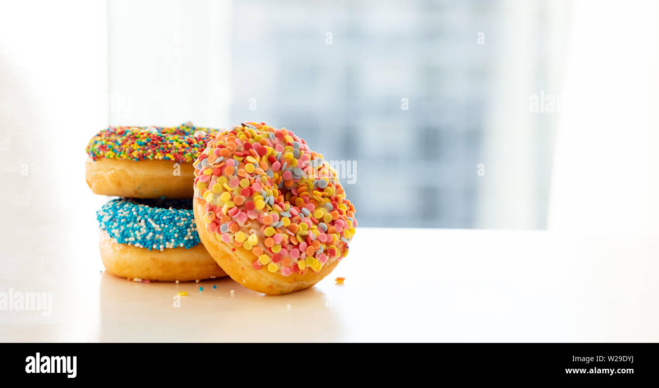 Donuts for breakfast. Colorful donuts on white table. Close up view, copy space Stock Photo