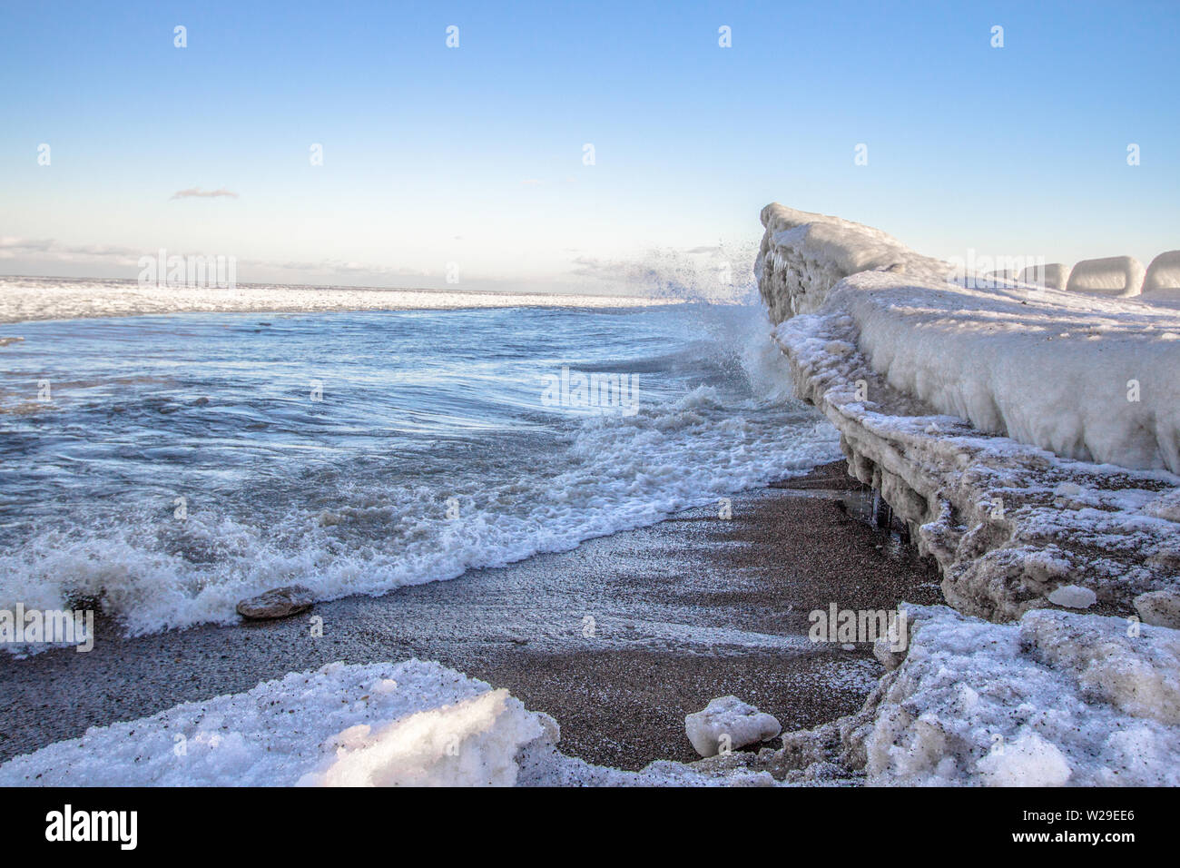 Winter On The Great Lakes. Ice on the frozen Great Lakes as waves splash on the coast on a cold winter morning. Port Sanilac, Michigan Stock Photo