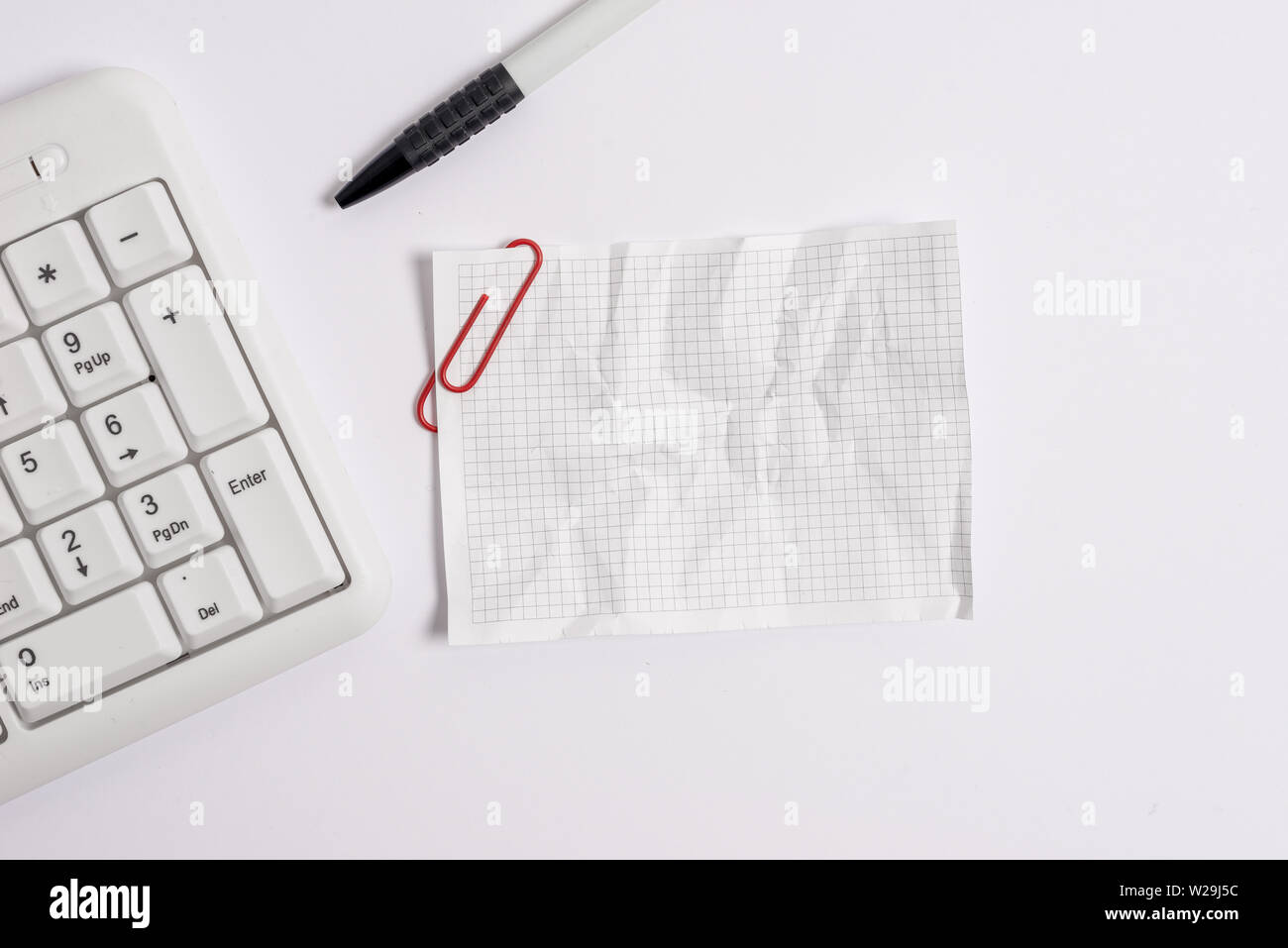White pc keyboard with empty note paper above white background ...
