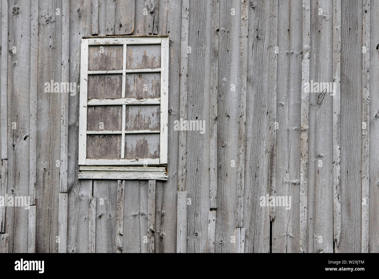 Textured Barn Wall Background. Weathered grey barn wall exterior with boarded up window. Stock Photo