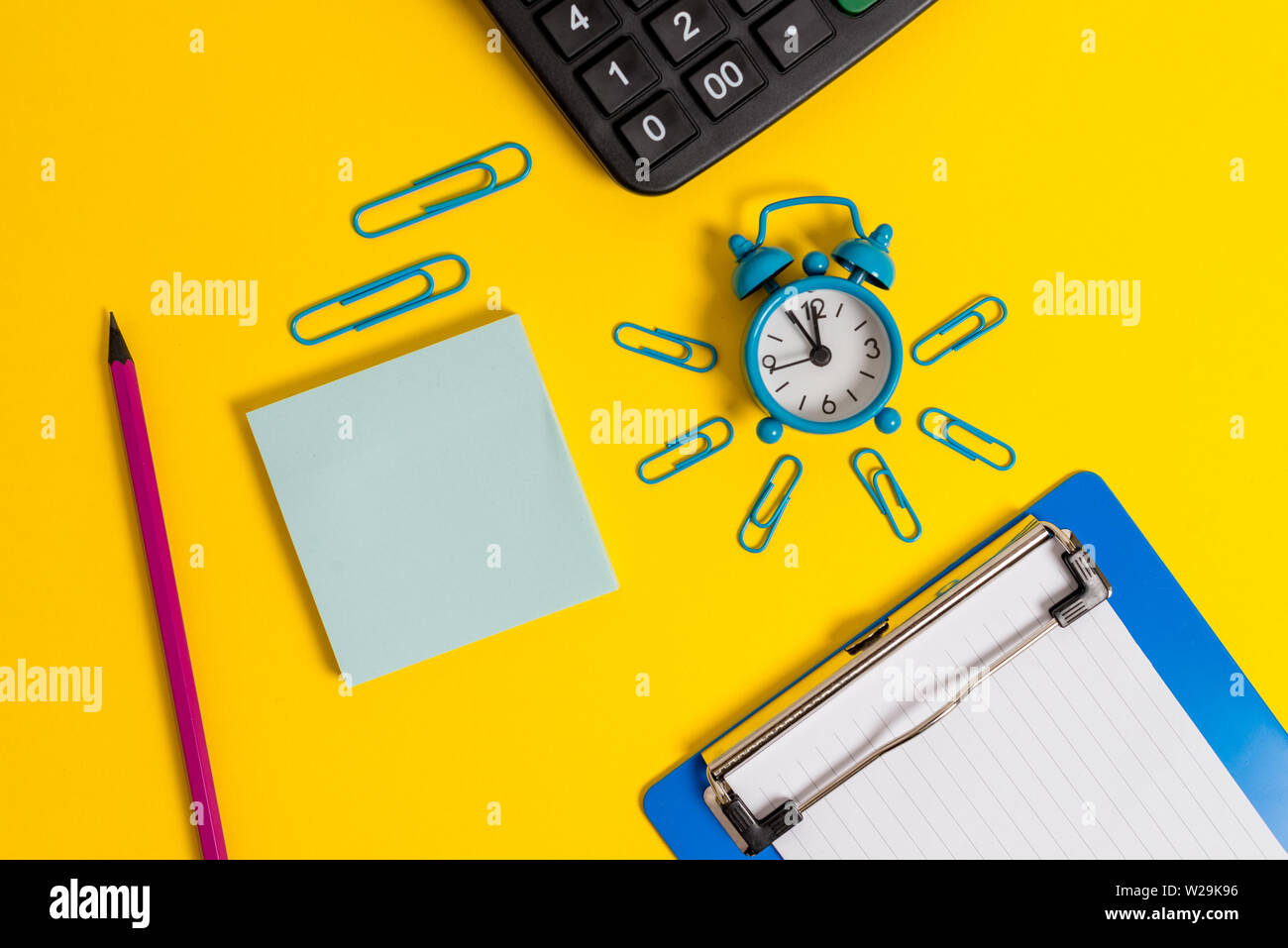 Alarm clock clipboard clips pencil calculator notepad colored background Stock Photo